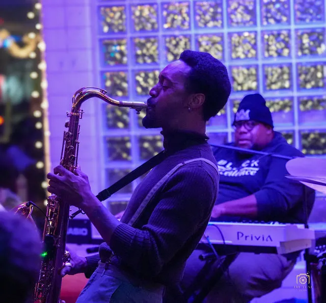 Saxophonist performing under purple event lighting