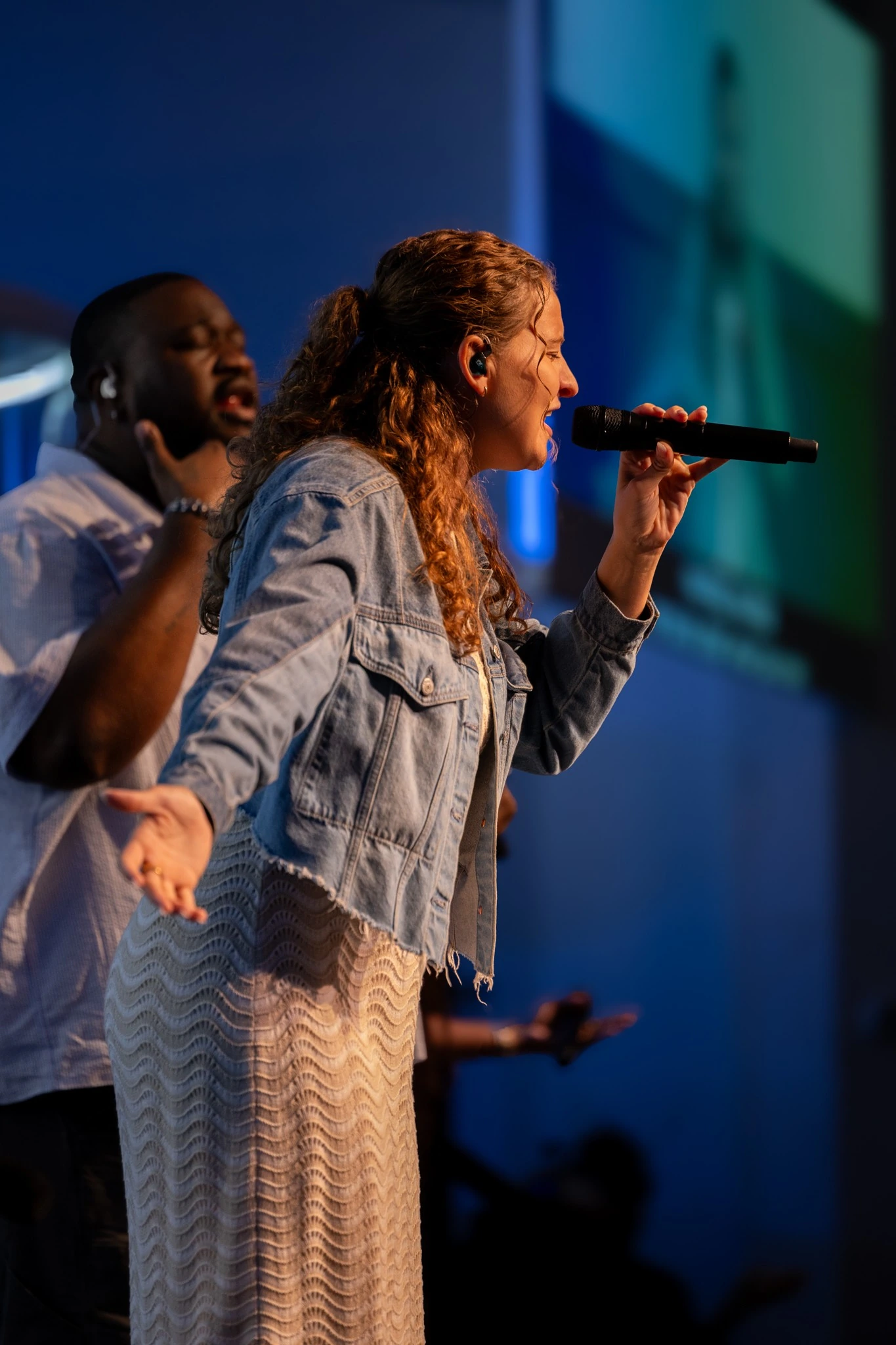Vocalist performing under blue stage lighting at a Houston live event