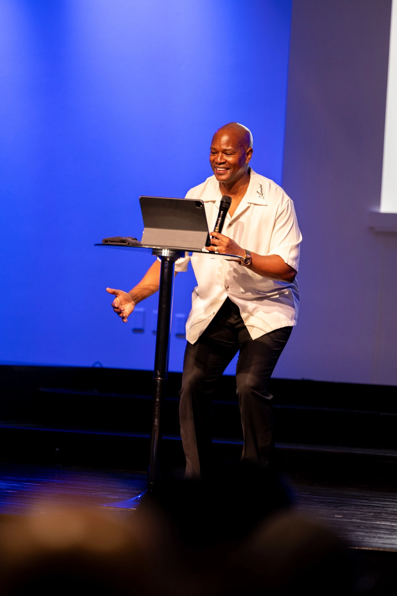 Featured speaker smiling at a lectern during a Houston stage program