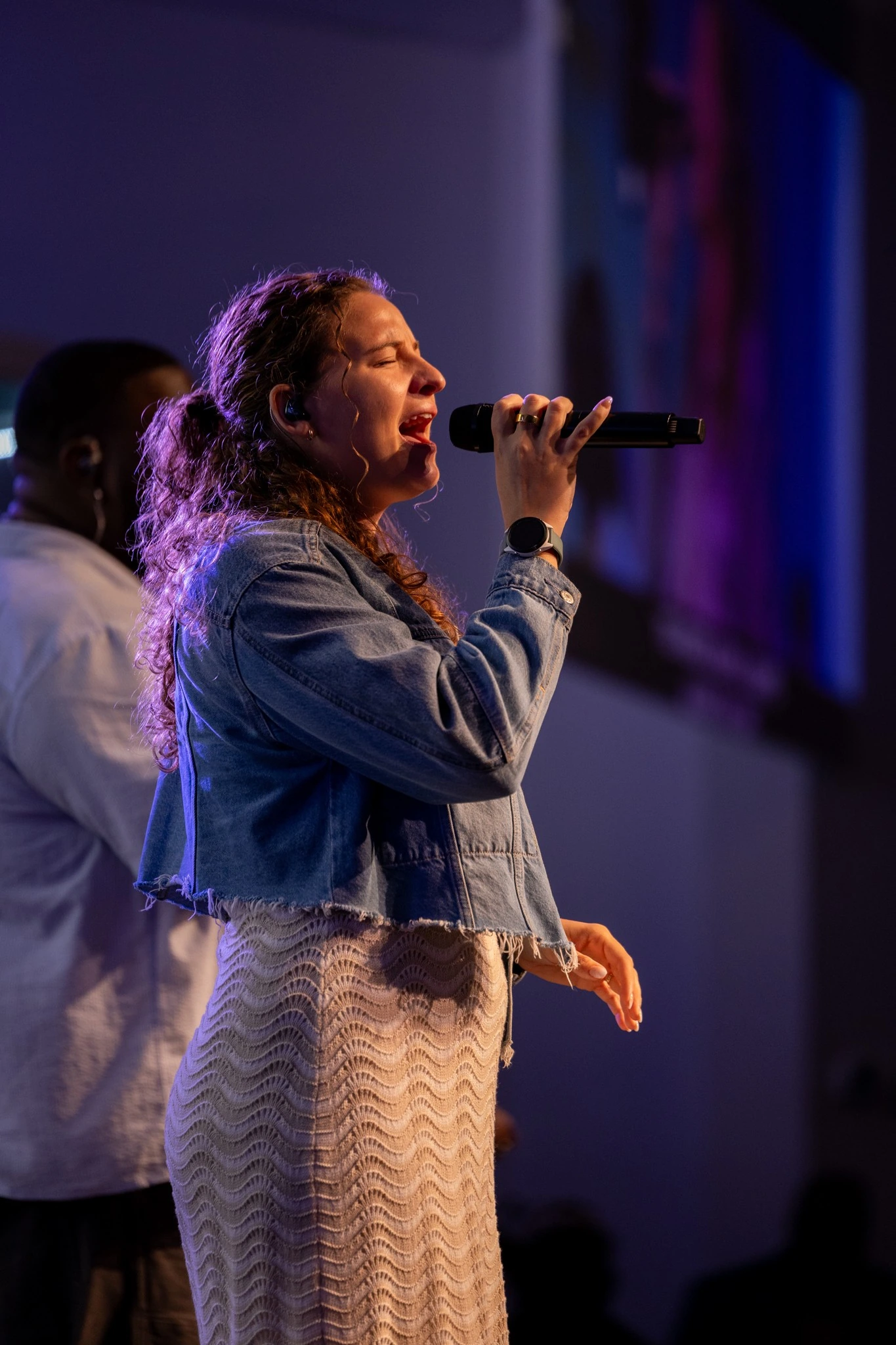 Vocalist singing under blue and purple event lighting