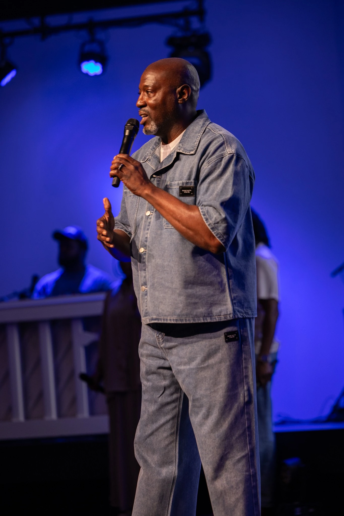 Speaker addressing attendees from a blue-lit stage
