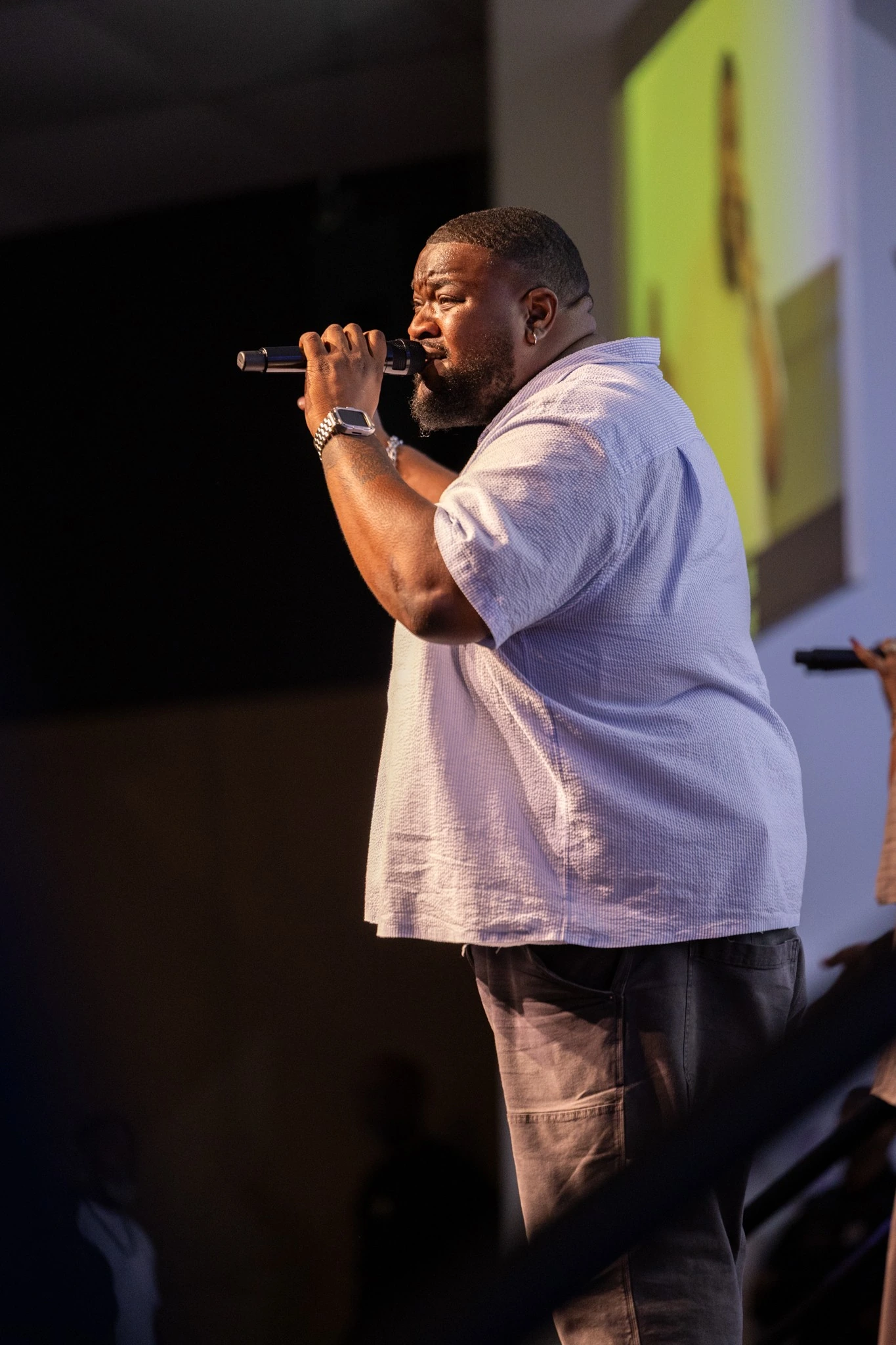 Male vocalist photographed in profile beneath stage lighting