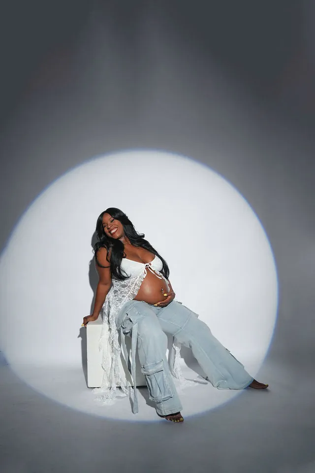 Joyful studio maternity portrait in a spotlight